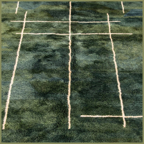 Lifestyle shot of a large green Moroccan rug with a geometric design in a natural setting.