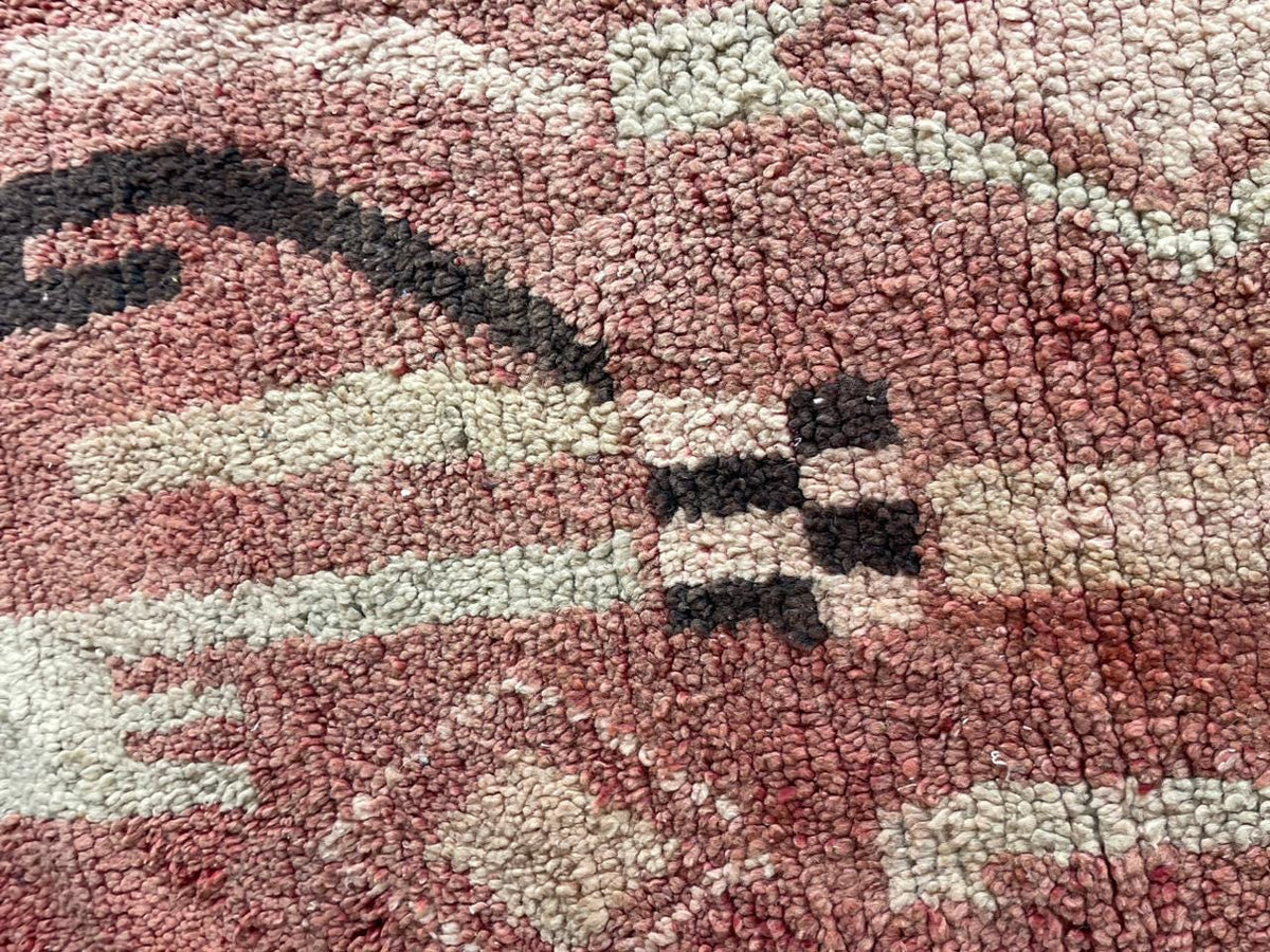 Close-up detail showcasing intricate motifs on a vintage Moroccan rug in red, black, and white.