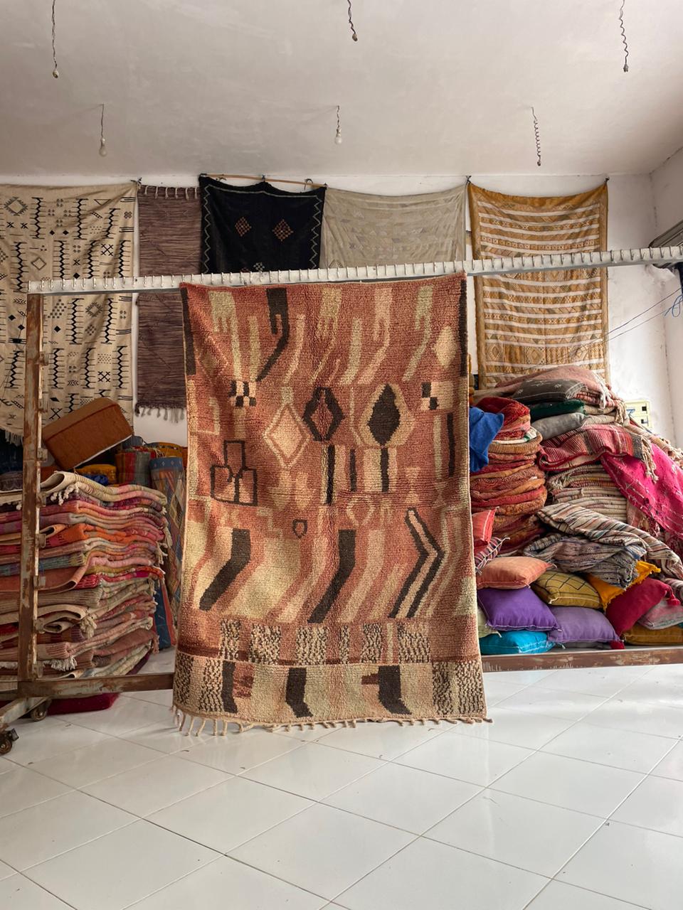 Lifestyle shot of a vintage Moroccan rug featuring tribal patterns in brown, red, and black.