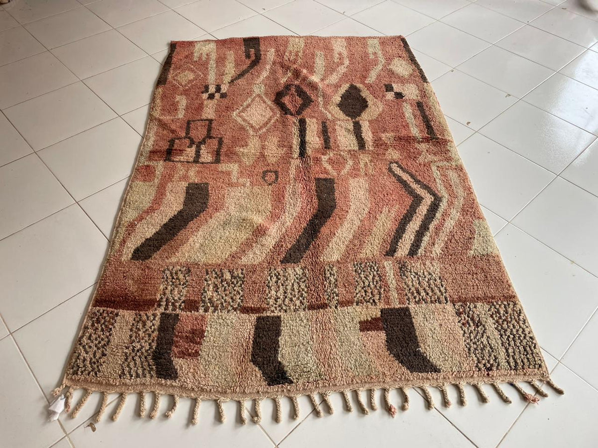 Front view of a vintage Moroccan rug with fringe edges and tribal designs in brown, red, and black.