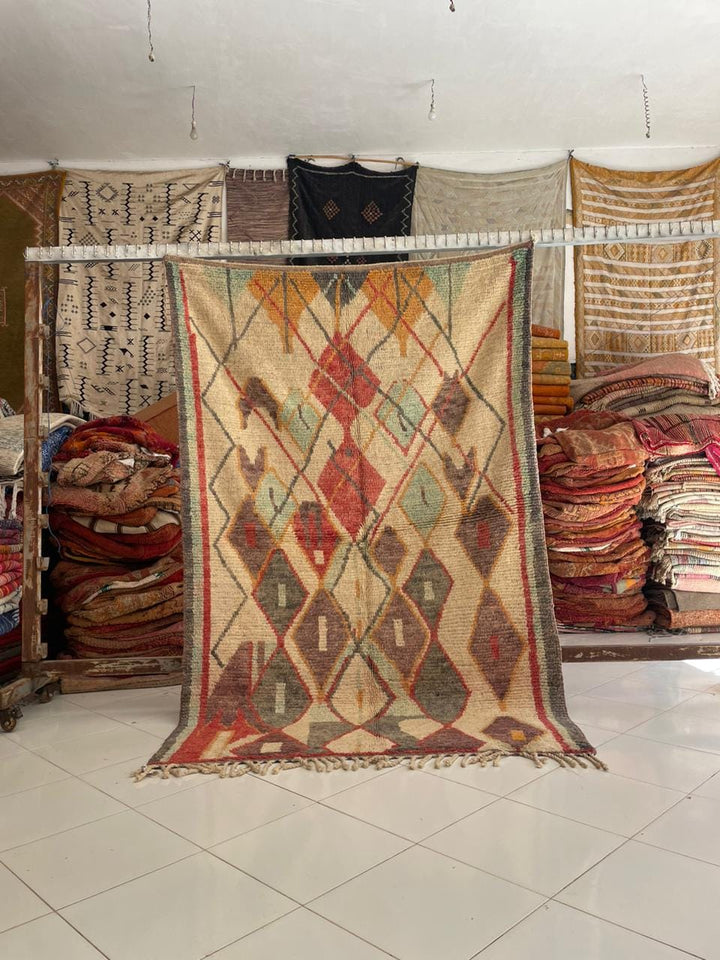 Lifestyle shot of a vintage Moroccan rug featuring tribal patterns in red, blue, and beige.