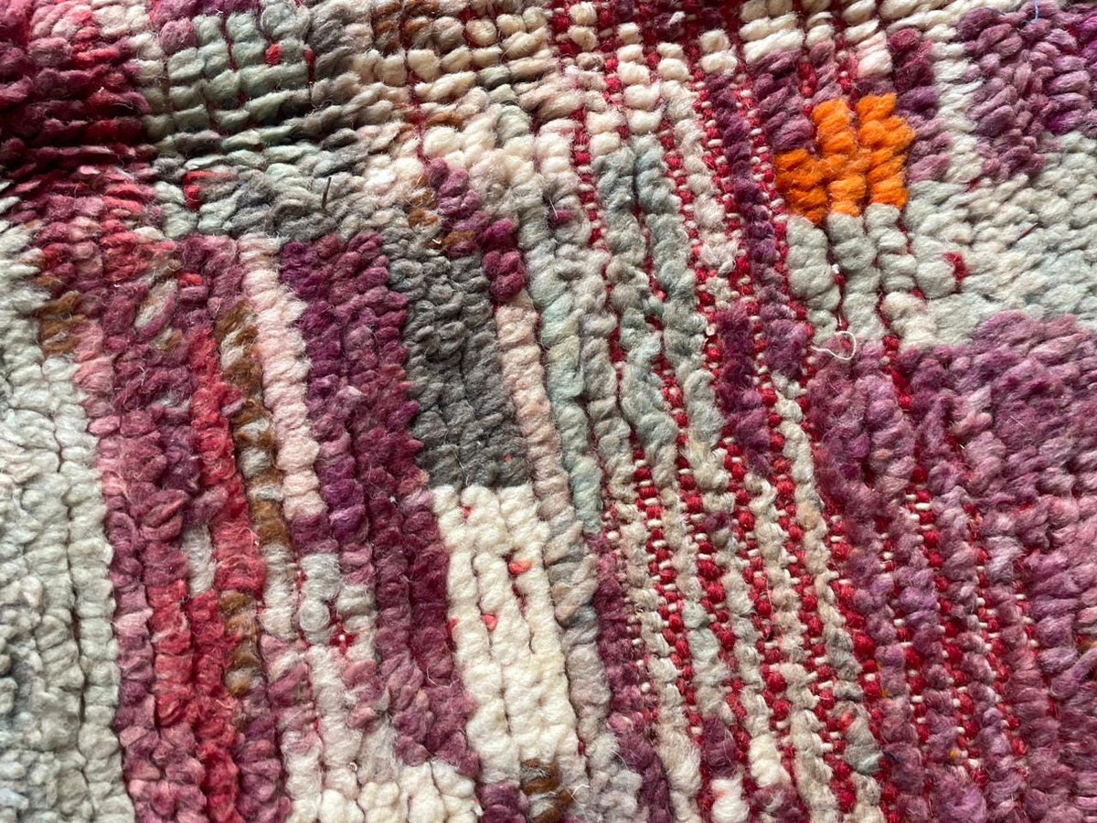 Close-up detail of a vintage Moroccan rug with textured weave and color variations in red and gray.