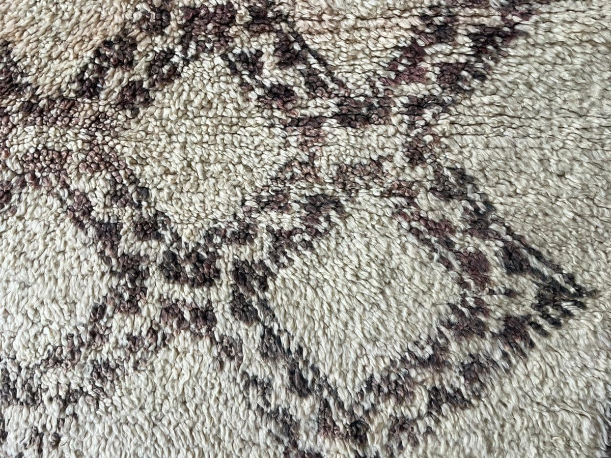 Detail shot showcasing the textured surface and intricate design of a beige and brown Moroccan rug.