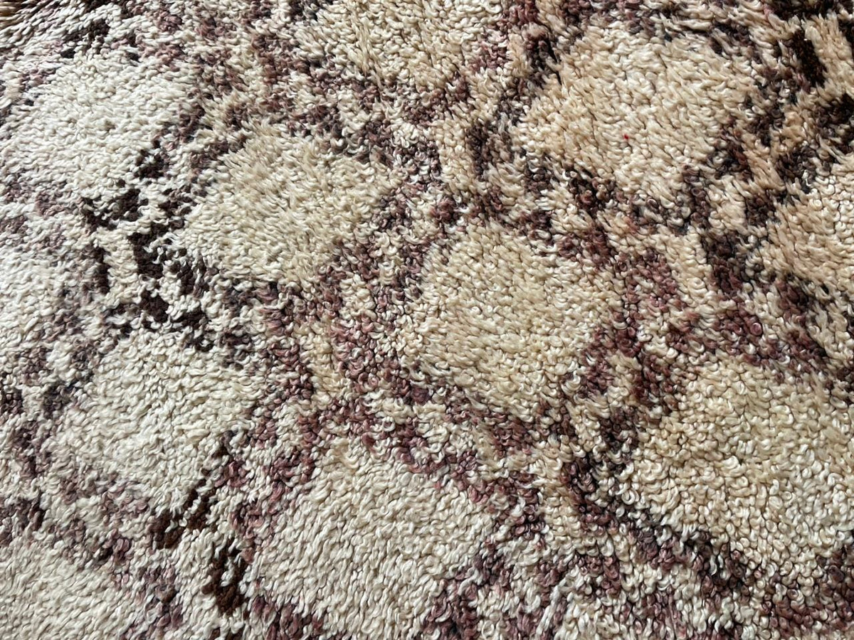 Close-up detail of the geometric pattern on a beige and brown Moroccan rug.