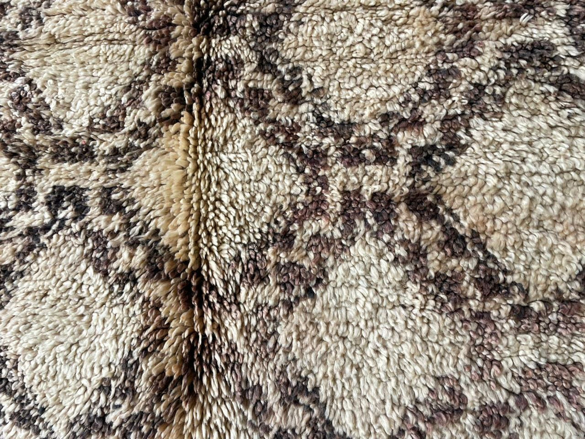 Detail shot highlighting the geometric pattern and texture of a beige and brown Moroccan rug.