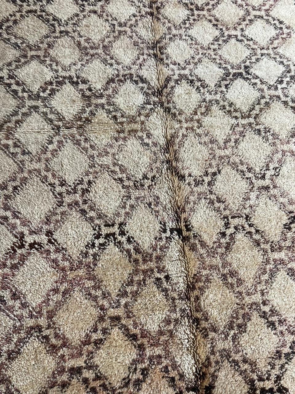 Close-up detail of the geometric pattern and textured surface of a beige and brown Moroccan rug.