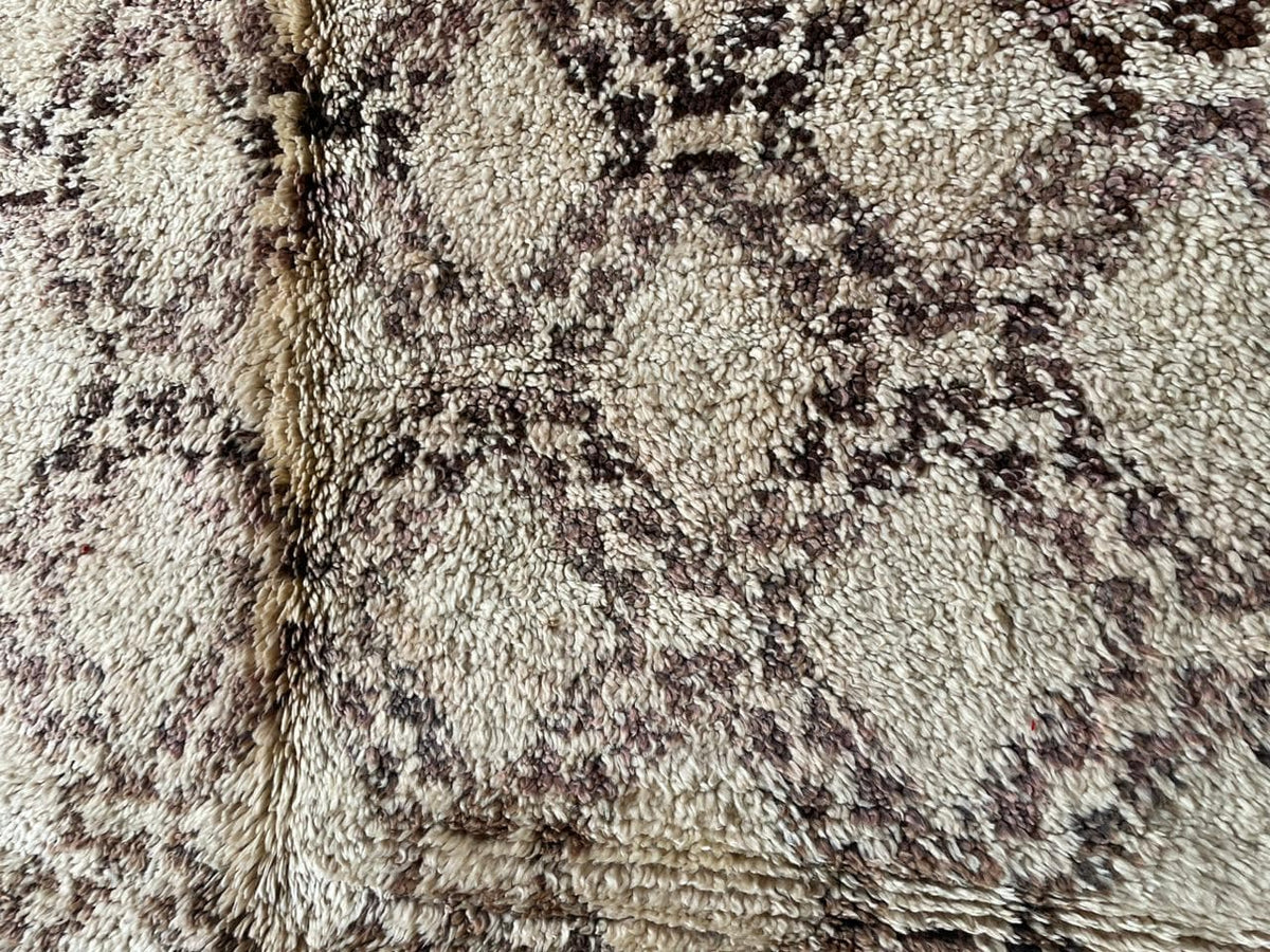 Close-up view of the geometric pattern and textured surface of a beige and brown Moroccan rug.