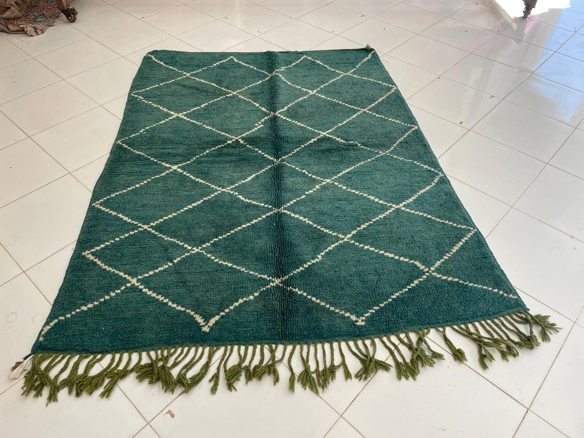 Front view of a green Moroccan rug featuring a diamond pattern against a solid color background.