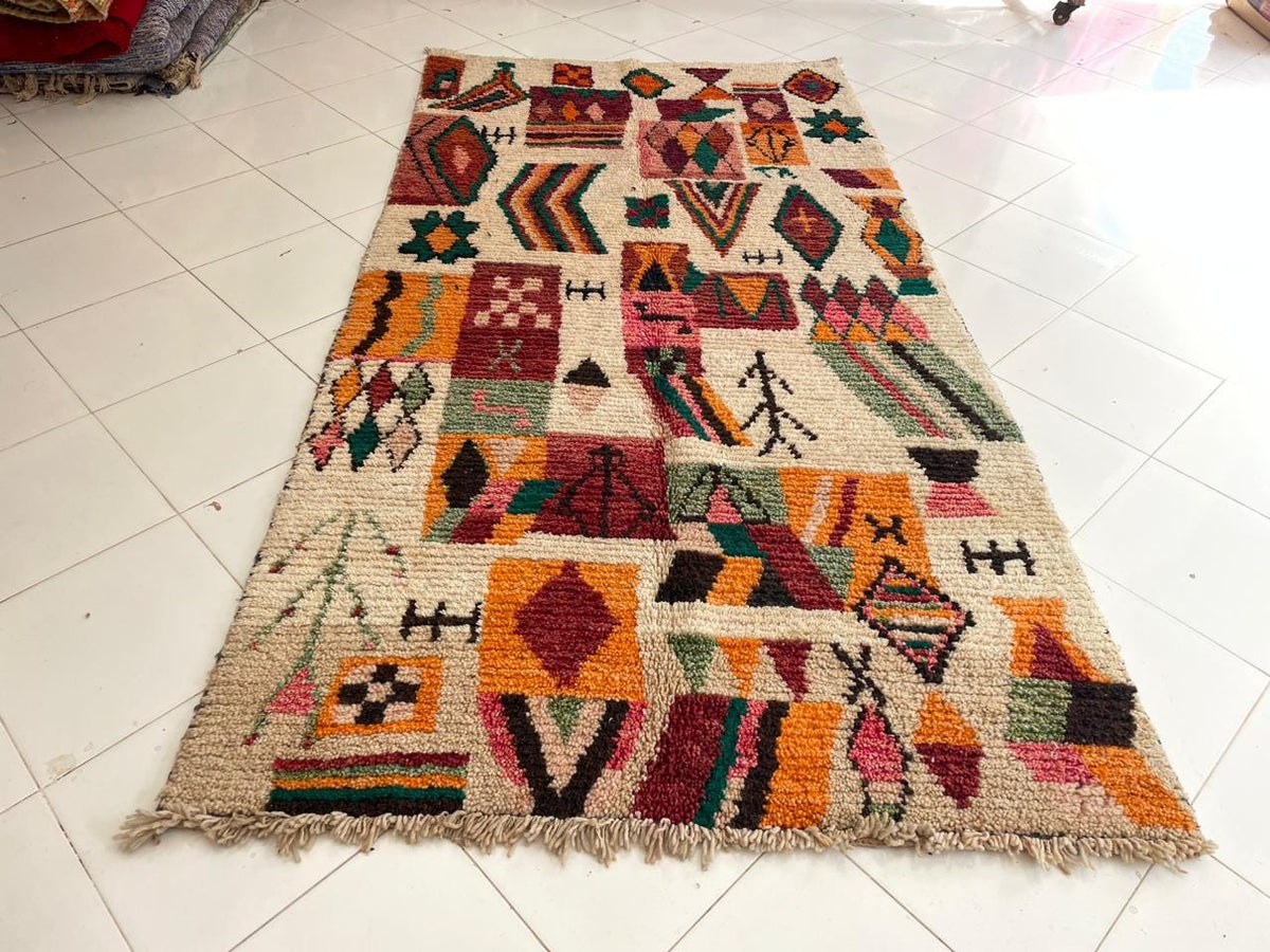 Lifestyle view of a Moroccan rug showcasing geometric designs in beige, orange, green, and red.