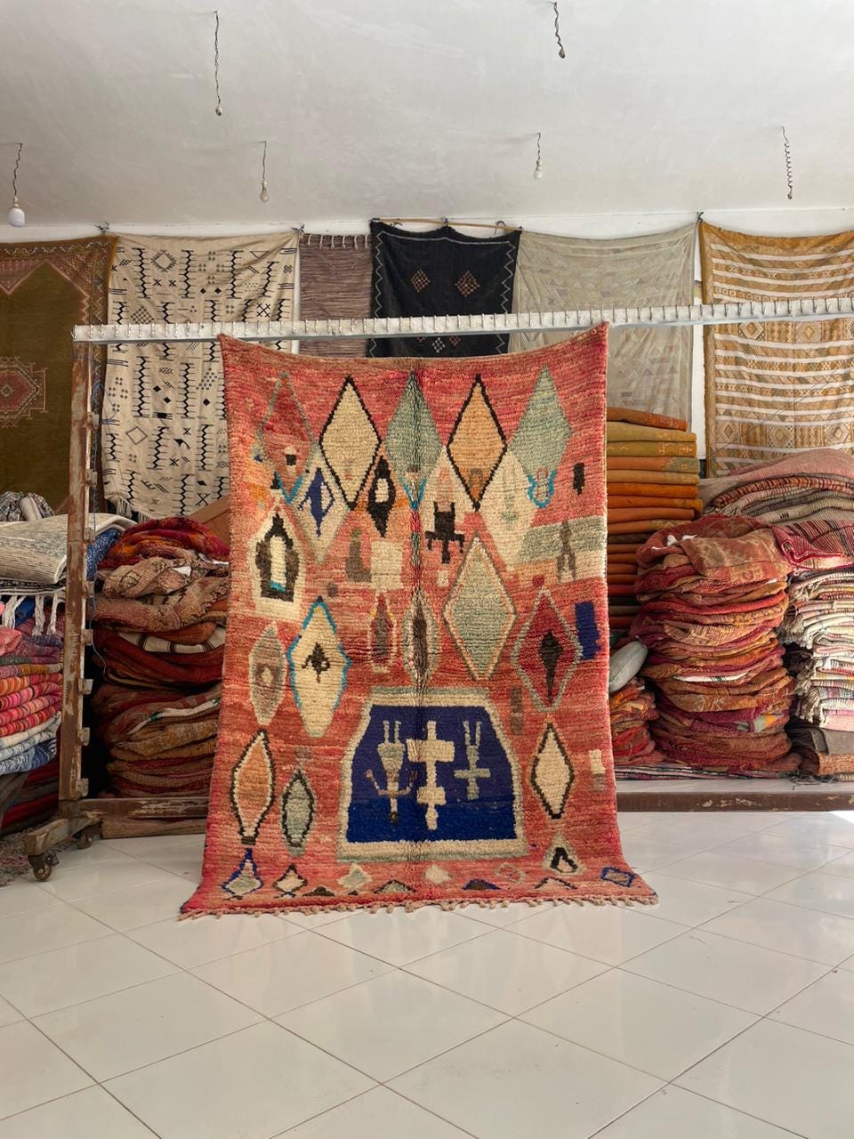 Lifestyle view of a Moroccan rug featuring geometric patterns in red, blue, and cream colors.