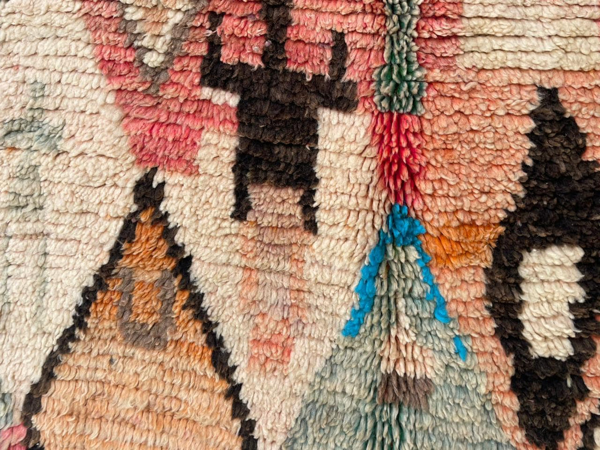 Detail shot of the textured fibers and colorful designs of a vintage Moroccan rug.