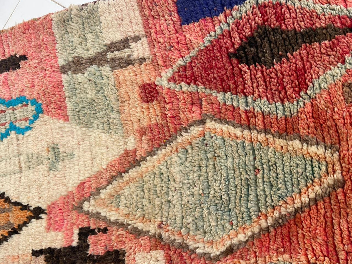 Detail view of abstract shapes and a textured surface on a vintage Moroccan rug.