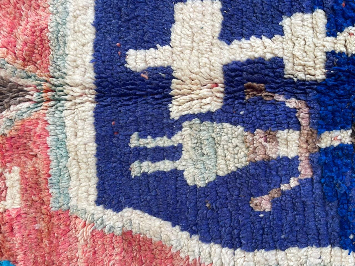 Close-up detail of diamond patterns and colorful designs on a vintage Moroccan rug.