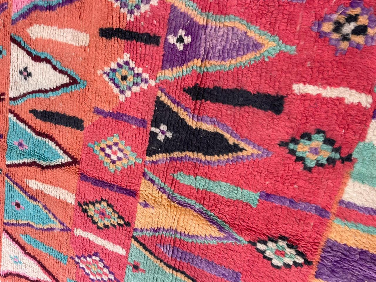 Front view of a vintage Moroccan rug showcasing abstract shapes in orange, pink, and green.