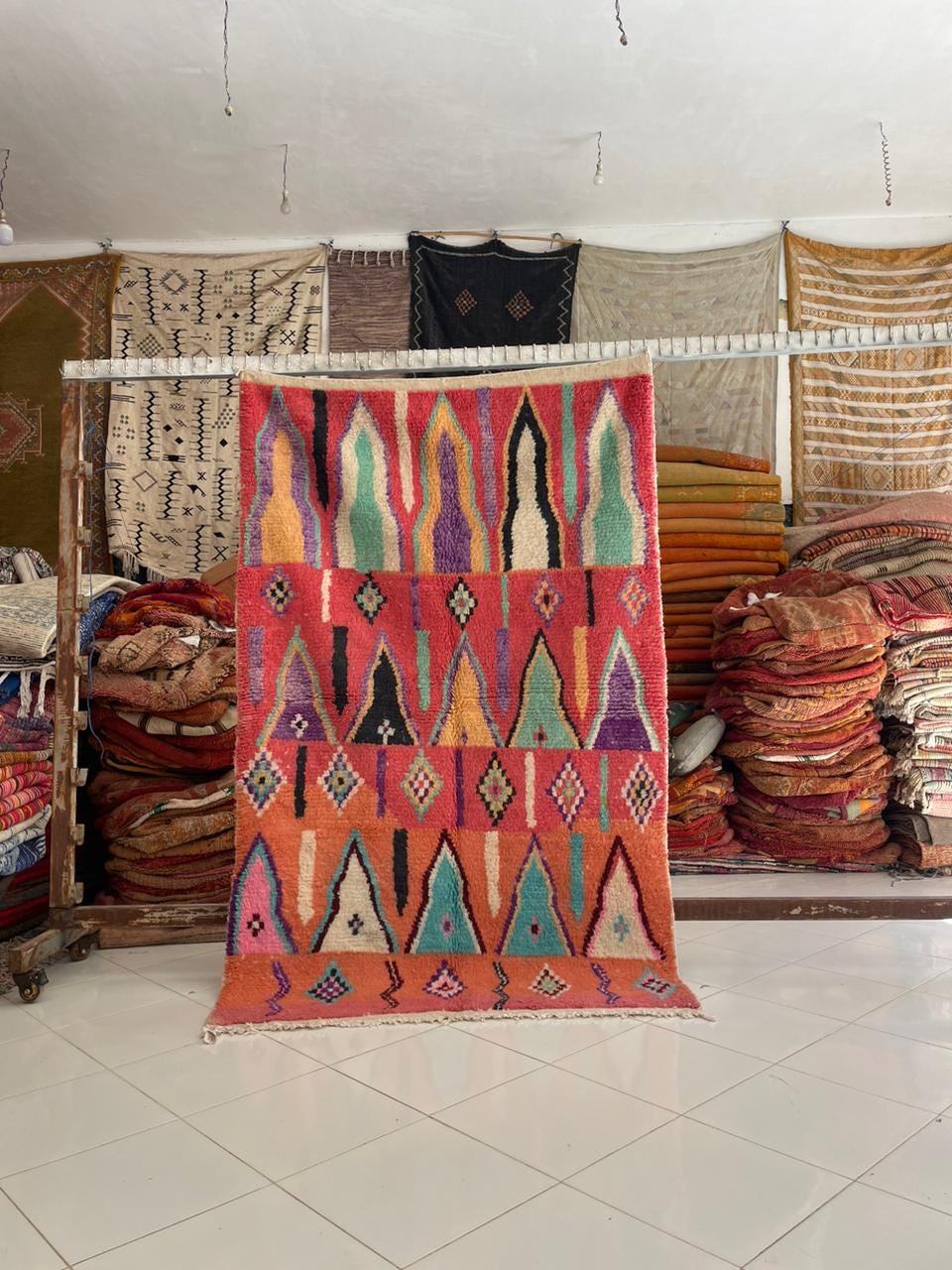 Lifestyle shot of a vintage Moroccan rug featuring geometric patterns in red, green, and purple.