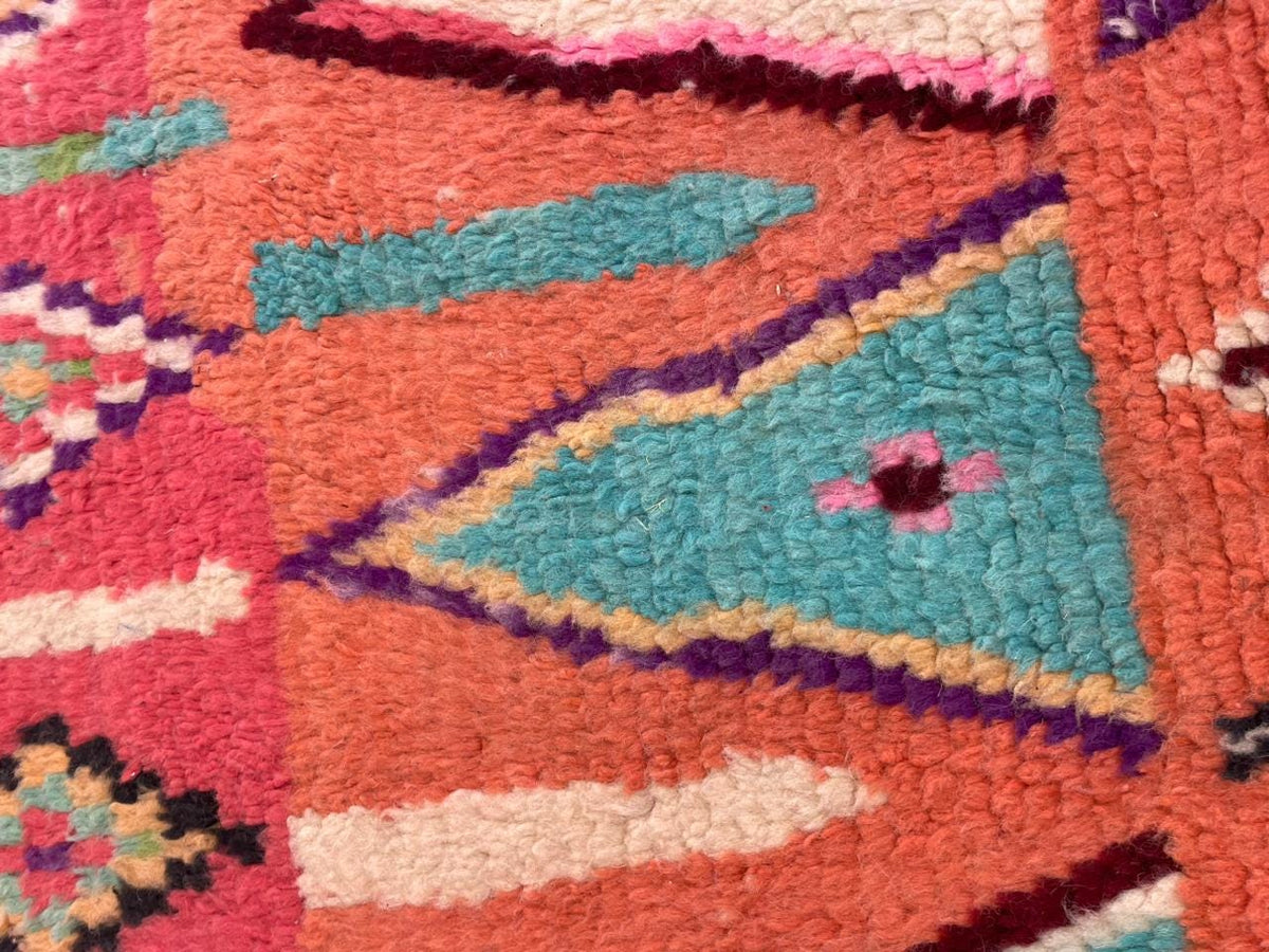 Detail close-up of a vintage Moroccan rug showcasing striped patterns in red, purple, and turquoise.