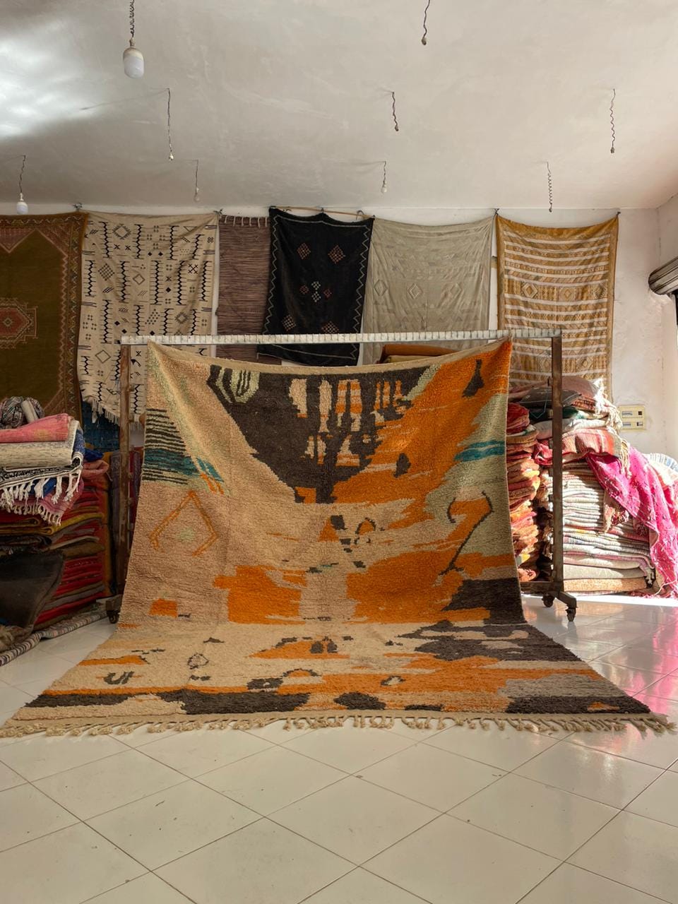 Lifestyle view of a vintage Moroccan rug featuring geometric patterns in orange, black, and beige.