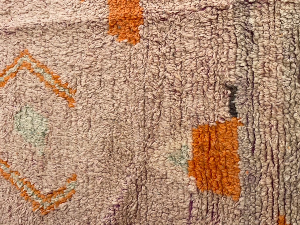 Detail shot of a vintage Moroccan rug showcasing a textured pattern with diamond shapes.