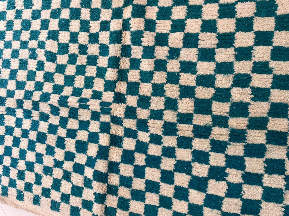 Detail close-up of the checkered design on a turquoise rug.