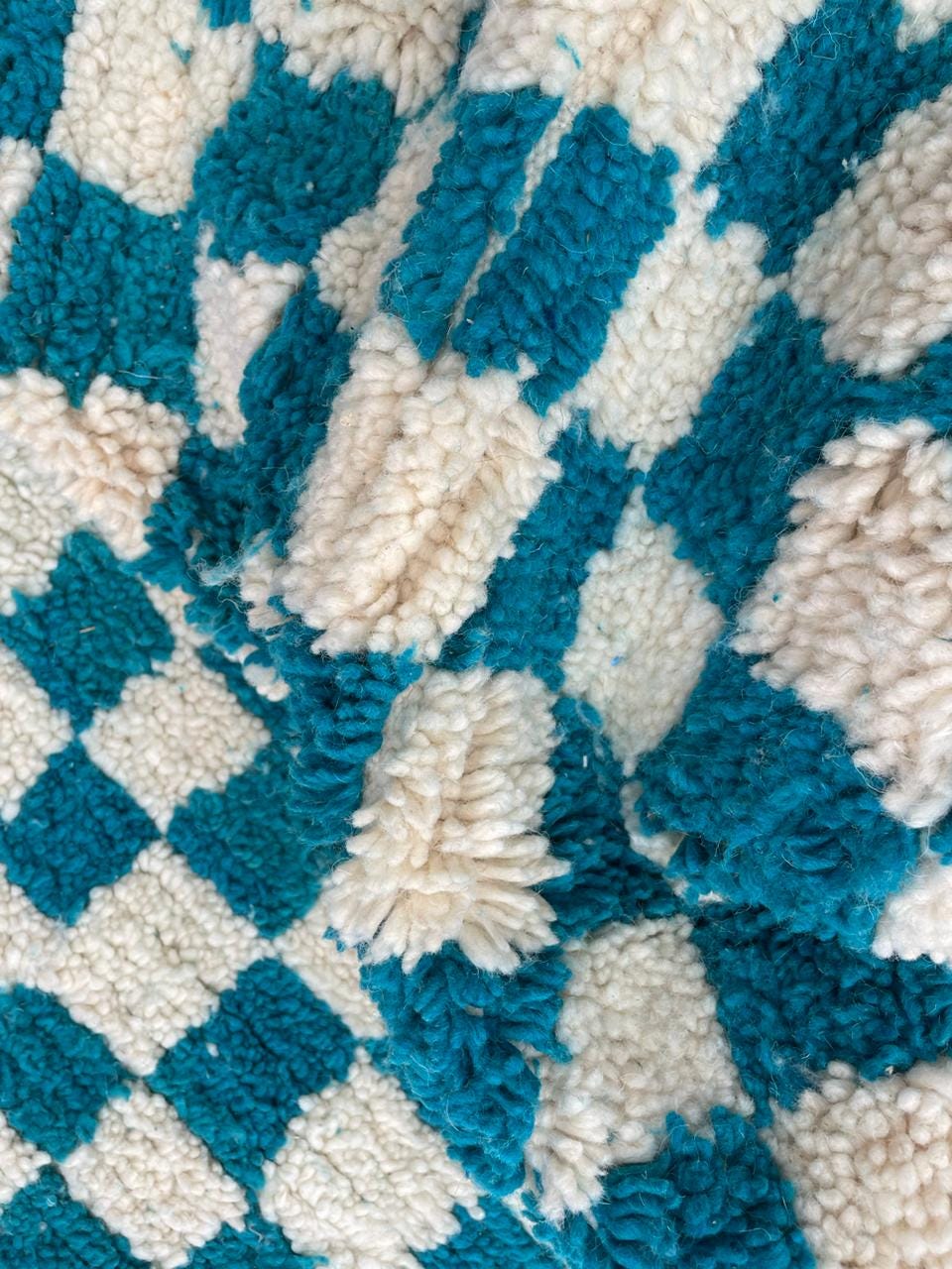 Detail shot of the soft texture and checkered pattern on a turquoise rug.