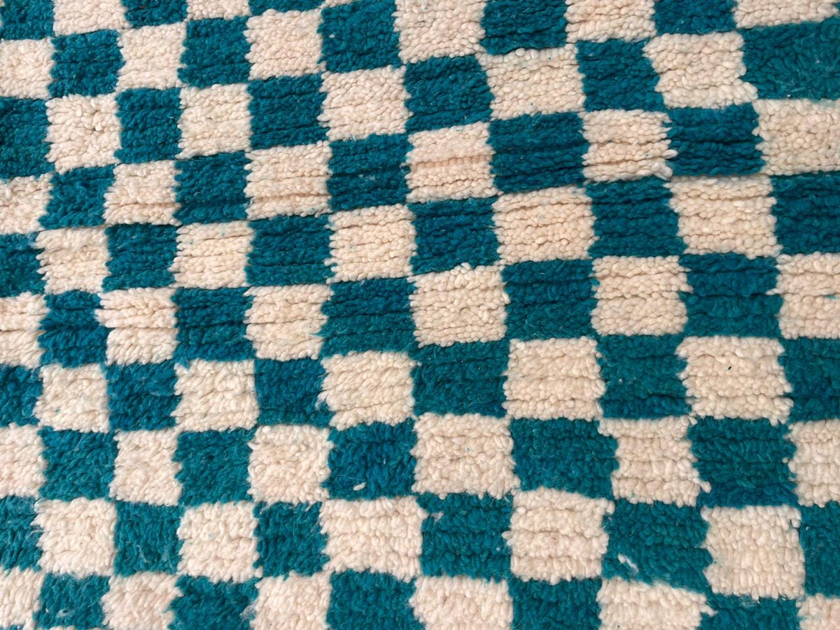 Close-up detail of the checkered pattern on a turquoise rug.