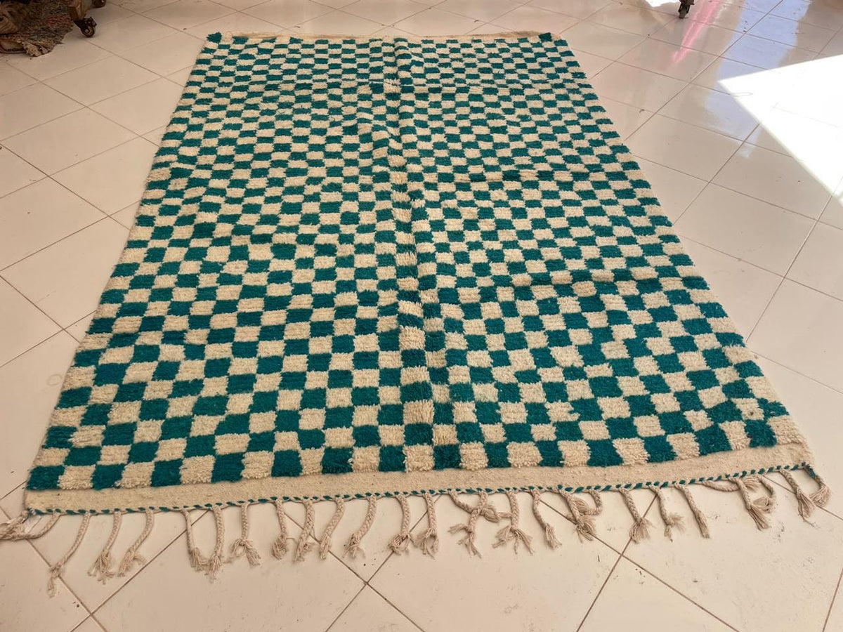 Detail close-up of the checkered pattern on a vintage turquoise rug.