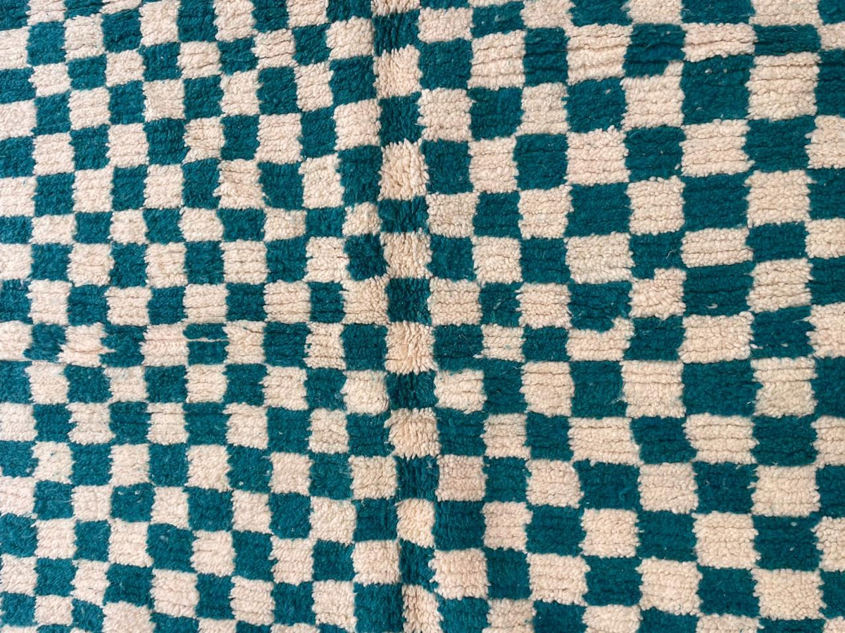 Detail shot of a checkered turquoise rug highlighting its pattern.