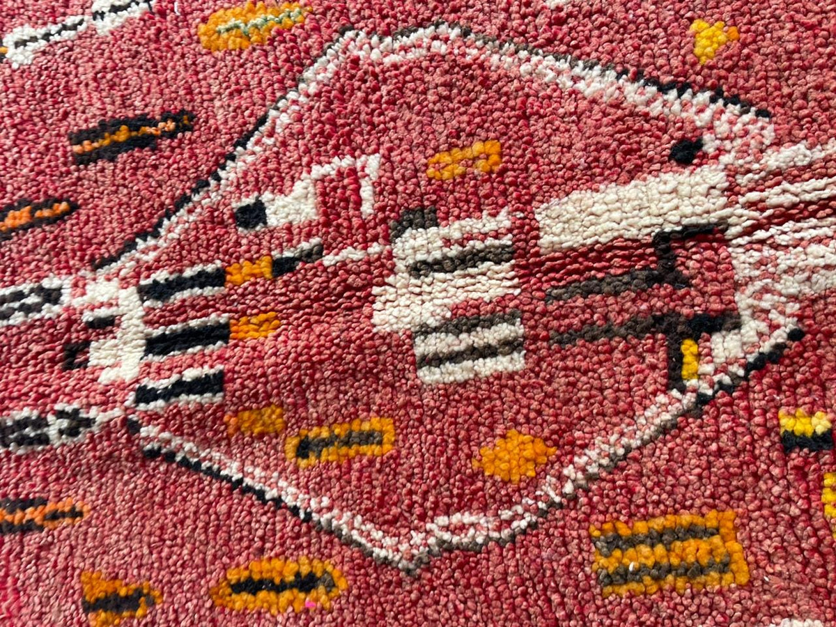 Close-up detail of a vintage Moroccan rug showcasing geometric shapes in red, white, black, and yellow.