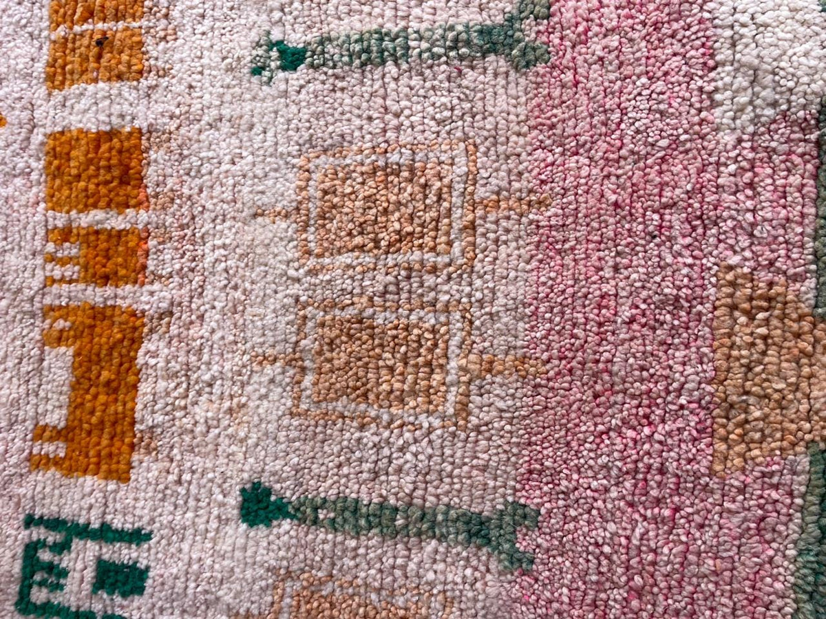 Close-up detail of a vintage Moroccan rug with tribal patterns in red, yellow, black, and white.