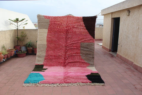 Lifestyle shot of a large pink geometric Moroccan rug with a textured surface.