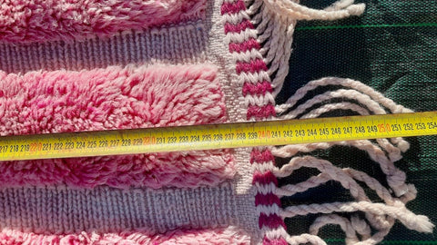 Close-up of a pink Moroccan rug highlighting its textured surface and fringe edges.