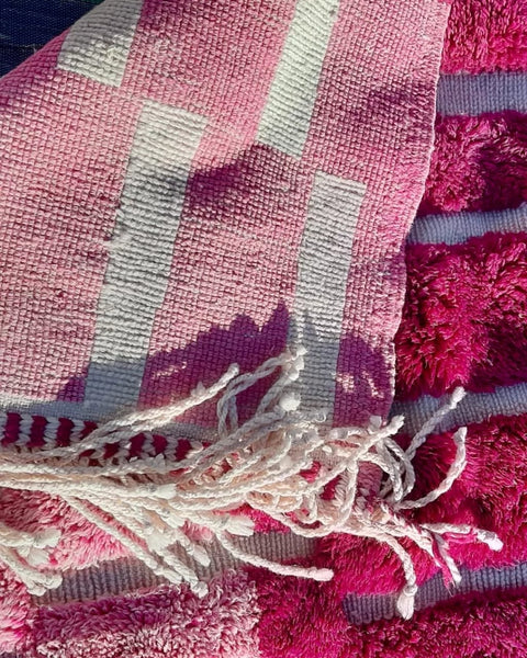 Front view of a pink Moroccan rug showcasing its geometric pattern and fringe edges.