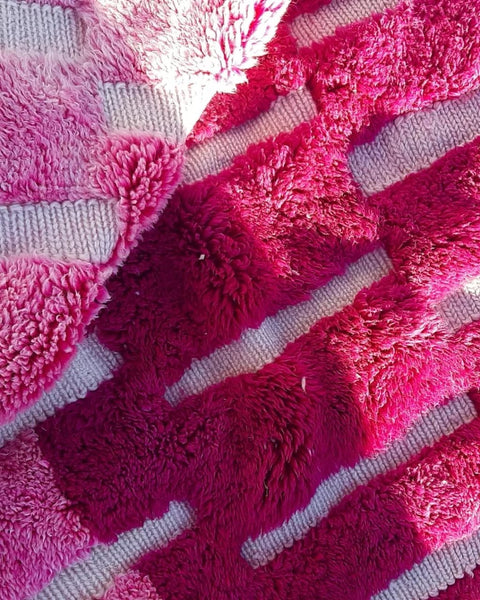 Close-up detail of the woven texture and fringe edges of a pink Moroccan rug.