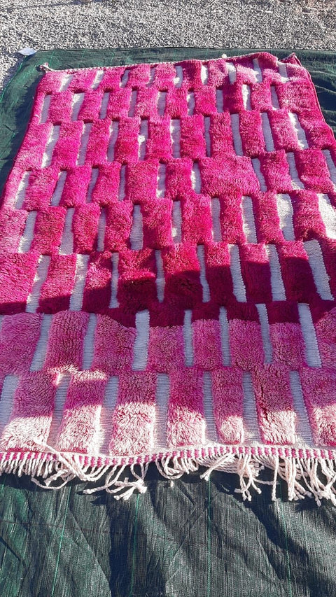 Close-up detail of a pink Moroccan rug featuring a patterned design and soft texture.