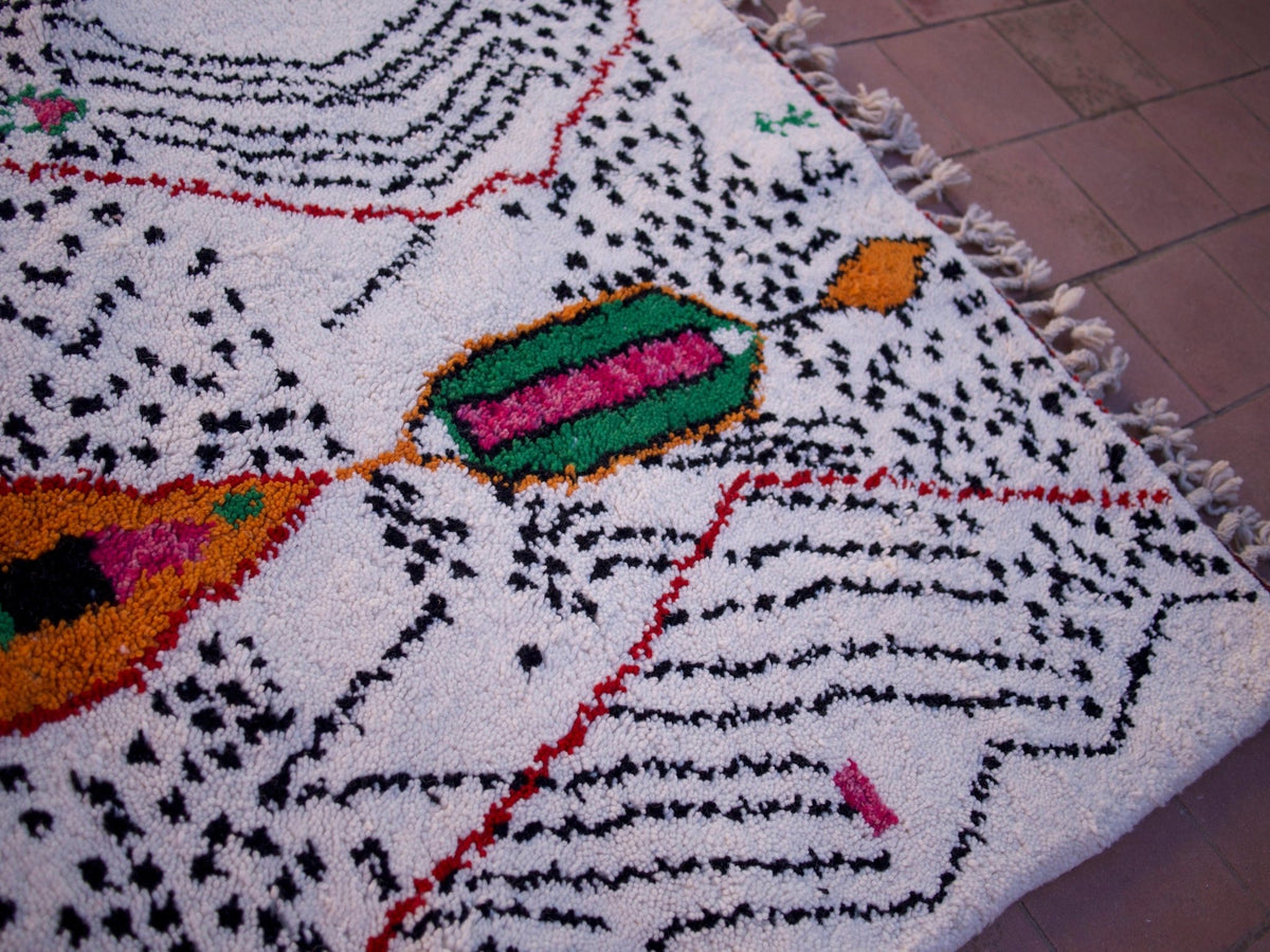 Detail view of a multicolor Moroccan rug highlighting geometric patterns and fringe edges.