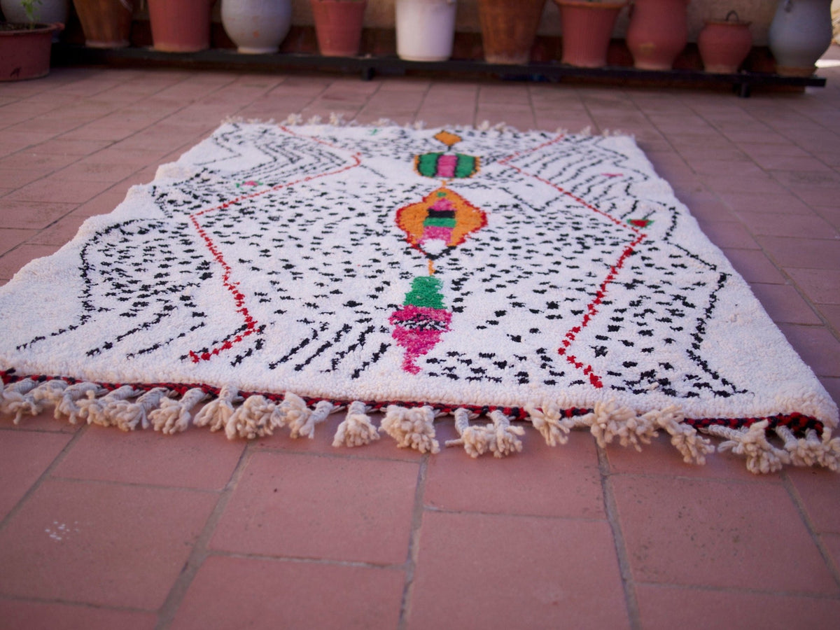 Lifestyle shot of a multicolor Moroccan rug with geometric patterns in a natural setting.