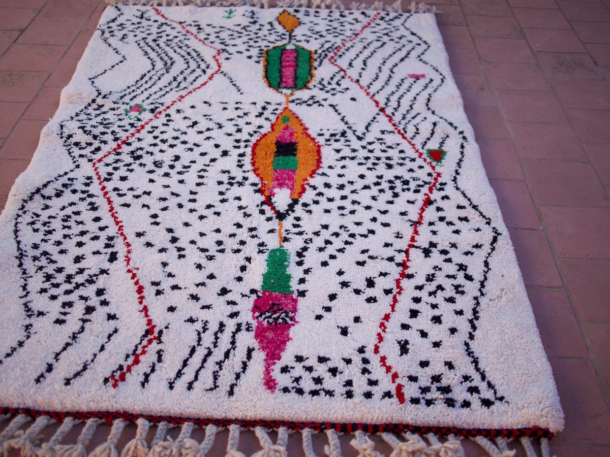 Detail view of a multicolor Moroccan rug featuring geometric patterns and fringe edges.