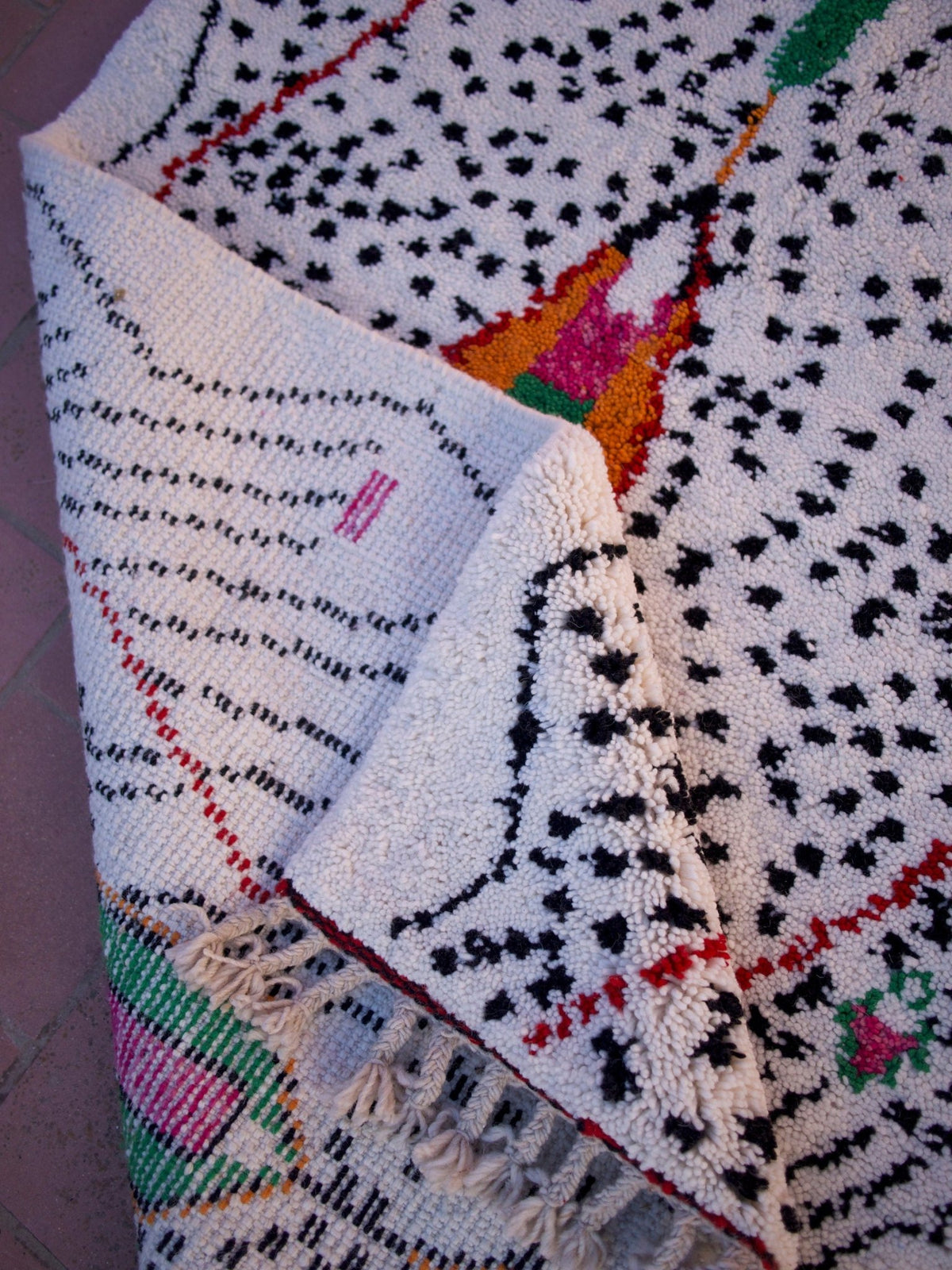 Detail view of a multicolor Moroccan rug with geometric patterns and colorful accents.