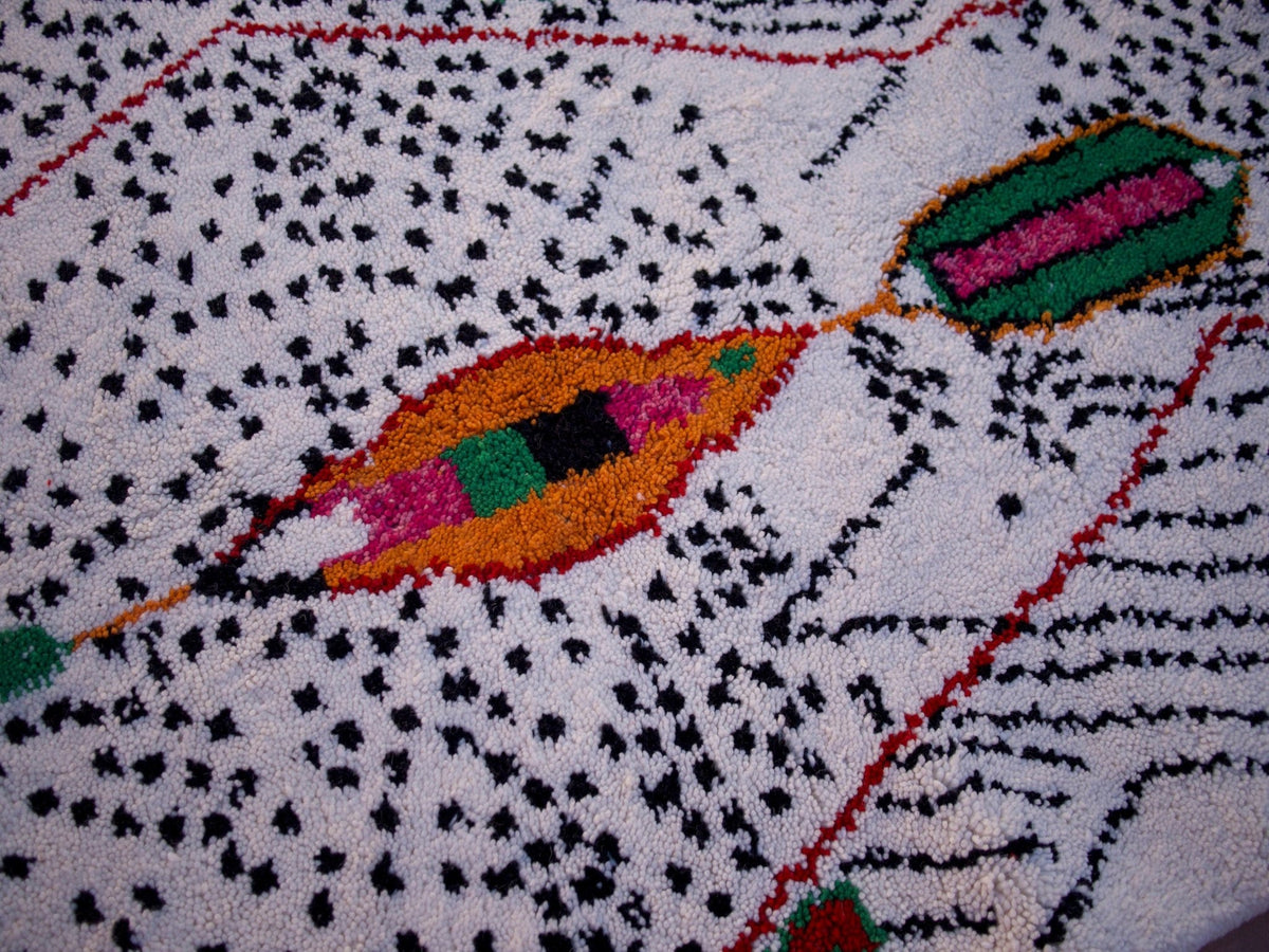 Lifestyle view of a large multicolor Moroccan rug with geometric designs in a natural background.