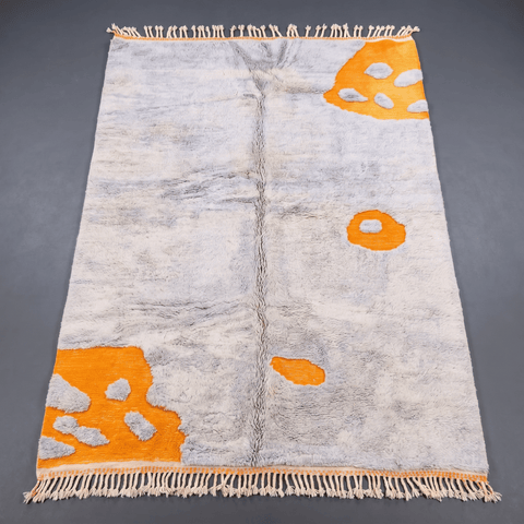 Front view of a light blue Moroccan rug featuring fringe edges on a solid color background