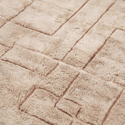 Close-up of light brown Moroccan rug featuring a textured pattern and soft fibers.