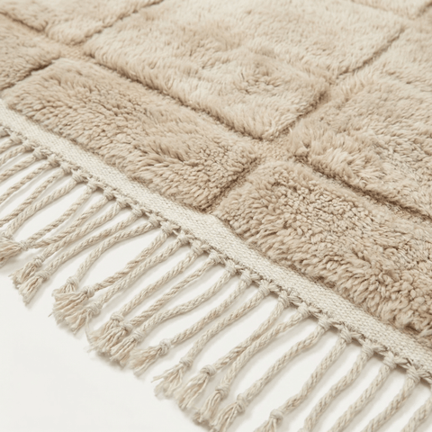 Detail shot of light brown Moroccan rug showcasing fringe and soft texture.