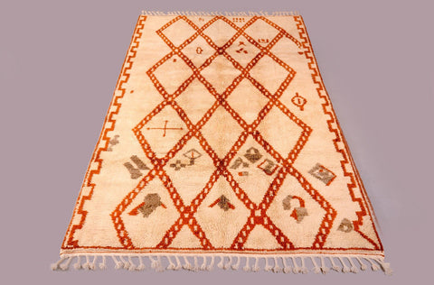 Close-up detail of the orange diamond patterned Moroccan rug showcasing its textured surface.