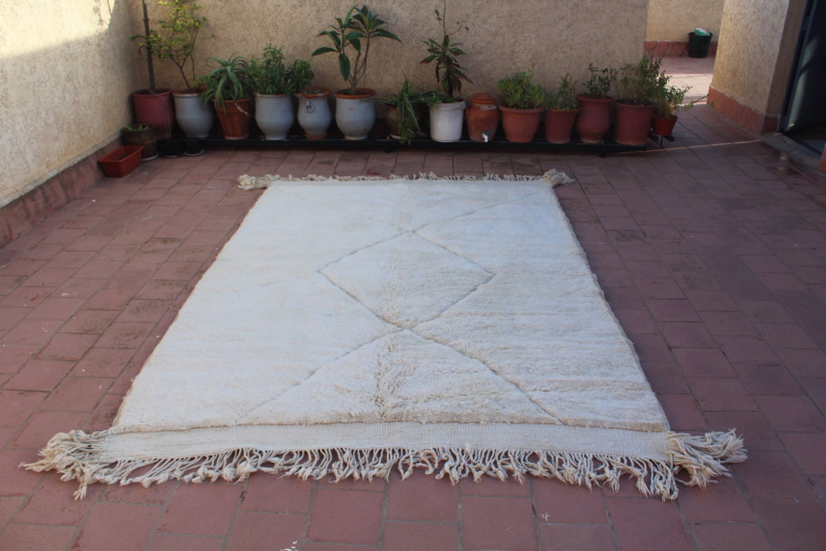 Top view of off-white tufted rug highlighting its tufted texture and fringe edges.