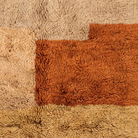 Close-up detail of the textured surface of the Moroccan rug showing geometric patterns in warm colors.