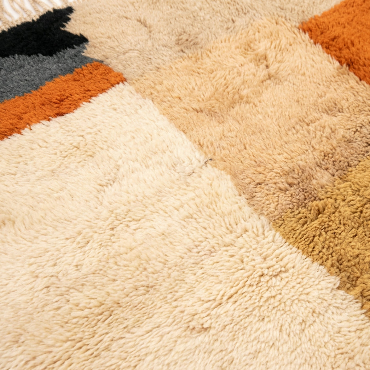 Close-up detail of the geometric patterns on the textured surface of the Moroccan rug in warm tones.