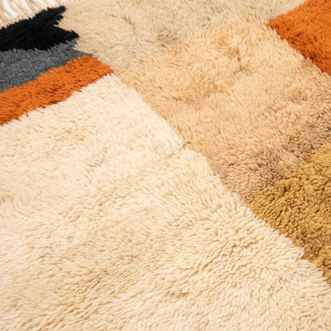 Close-up detail of the geometric patterns on the textured surface of the Moroccan rug in warm tones.