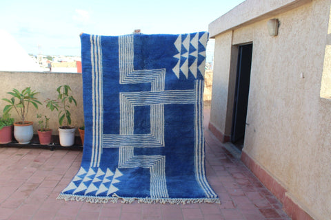 Lifestyle shot of a blue and white rug in a natural setting with a distinctive design.