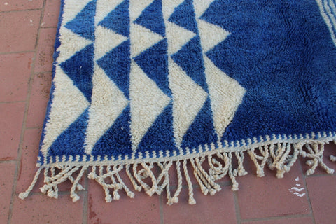 Close-up detail of a blue and white rug with fringed edges.