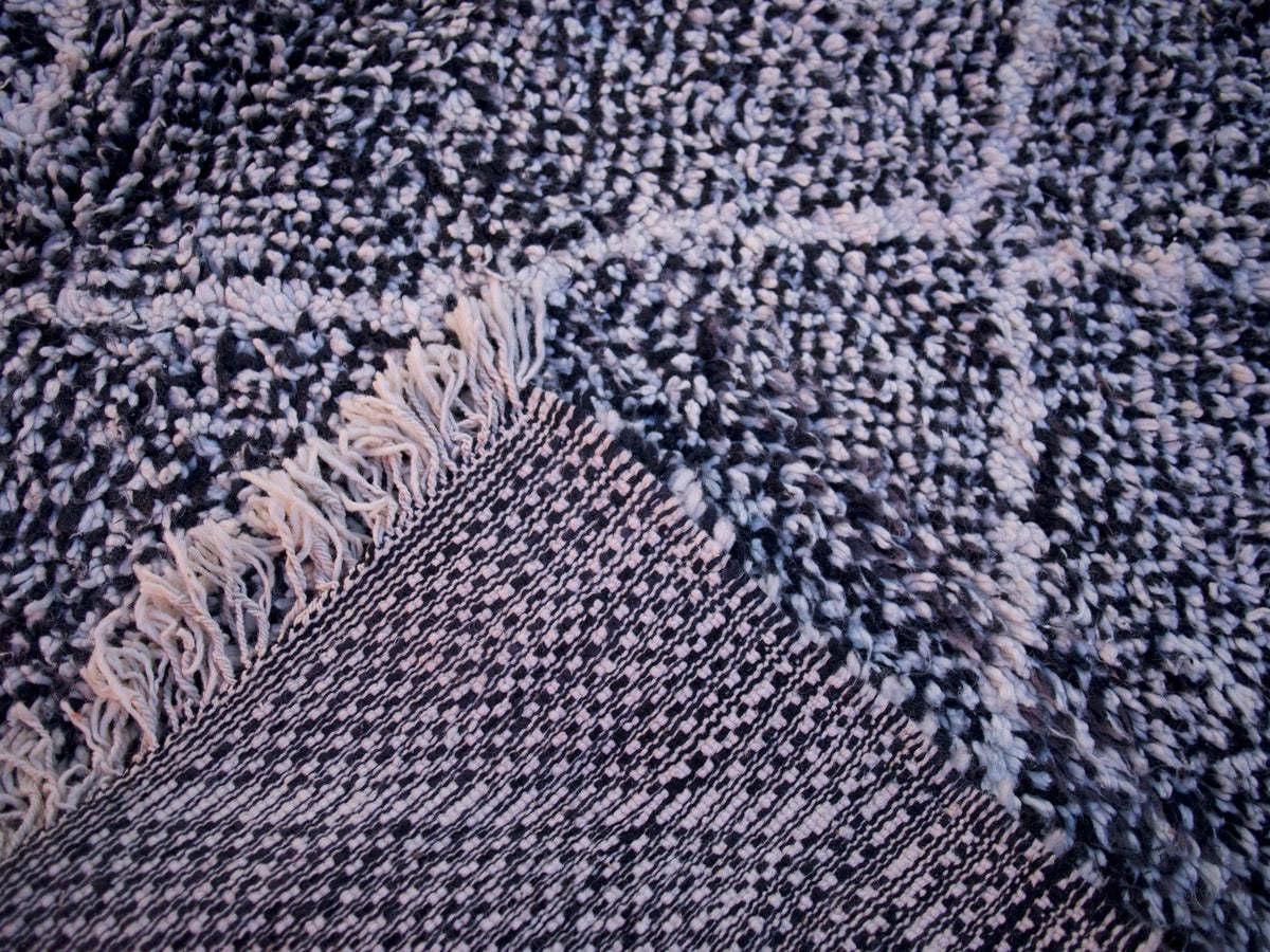Close-up detail of the geometric pattern on the black and white Beni Ourain rug.